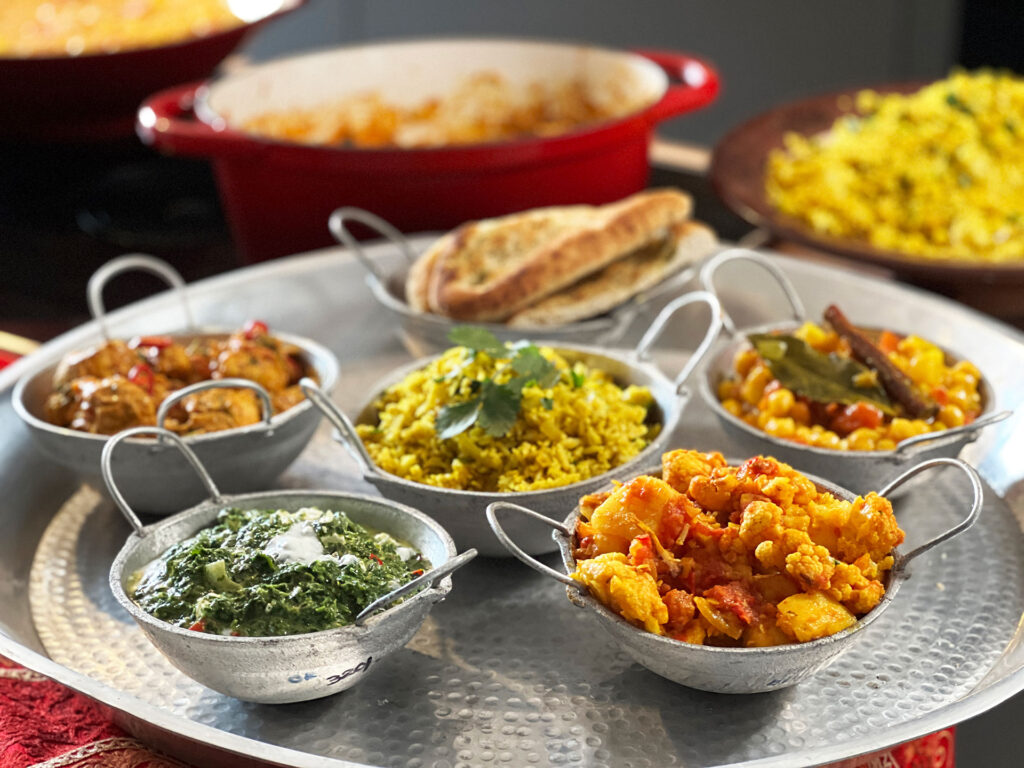 Indiase Thali. Een dienblad vol schaaltjes gevuld met curry's, chapati, kruidige rijst, samosas, raïta en groenten die op verschillende manieren bereid zijn.