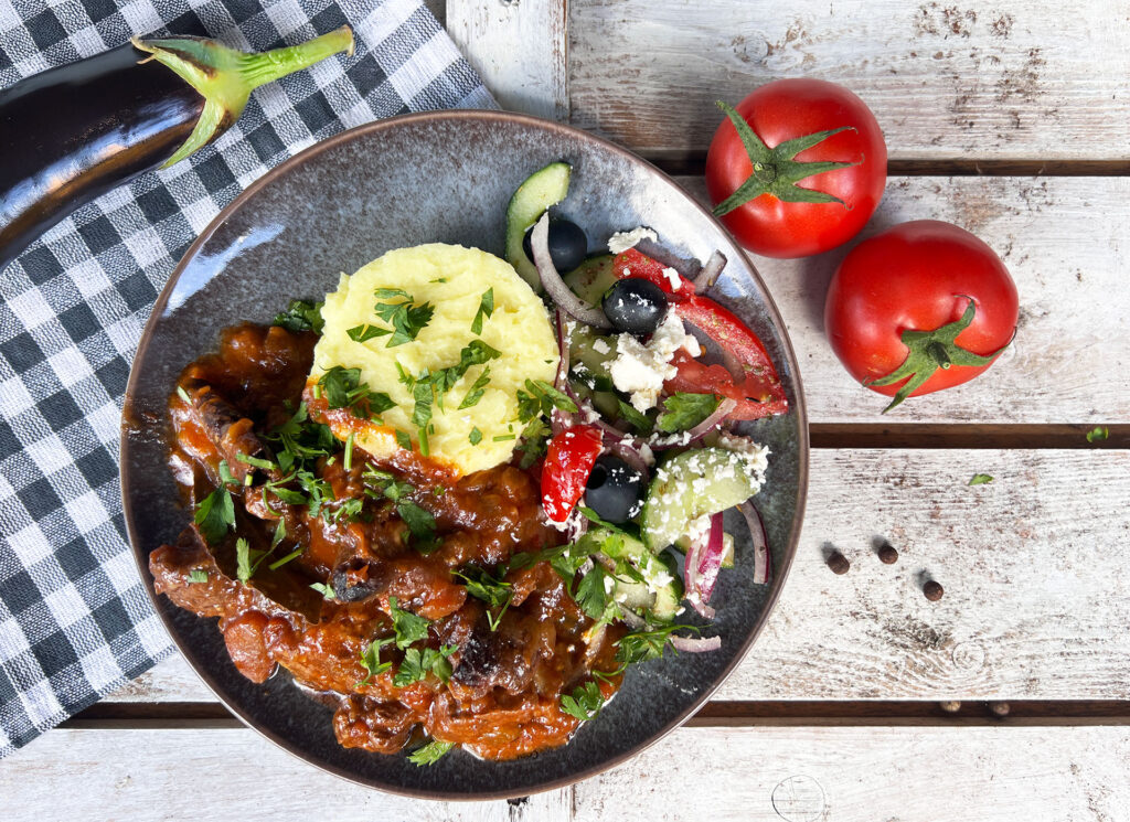 Stifado met rundvlees geserveerd met aardappelpuree en Griekse salade