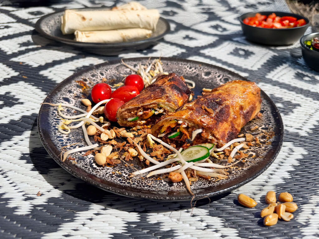 gado gado wrap met ei, pindasaus, taugé en komkommer op campingbord