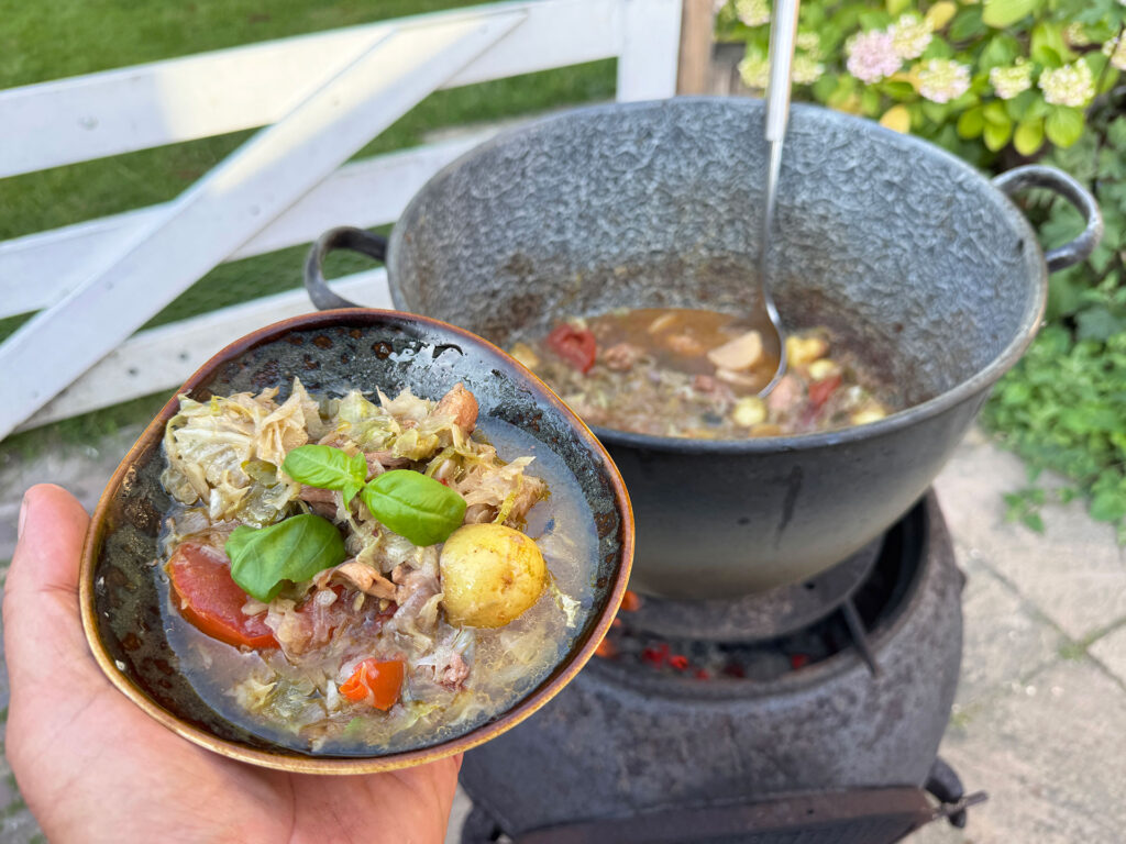 Stoofgerecht met kip, aardappel en groenten op open vuur in stoofpan