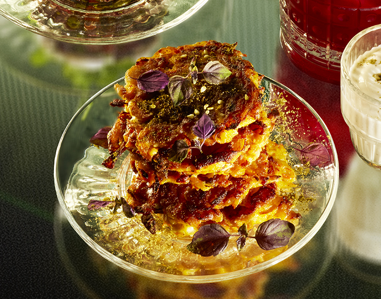 Pompoenfritters met feta en za’atar op een glazen bord