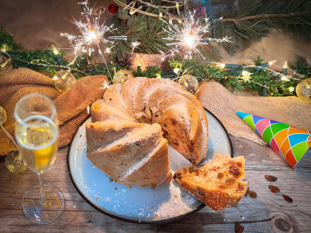 Oliebollencake uit de oven in tulbandvorm met poedersuiker.