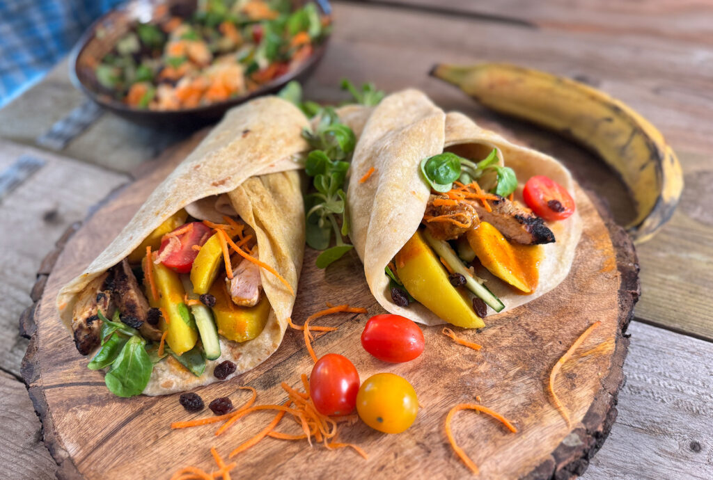 Picknick roti-rol gevuld met gegrilde masala kip, aardappel, bakbanaan, veldsla, cherrytomaat, wortel en groene appel.
