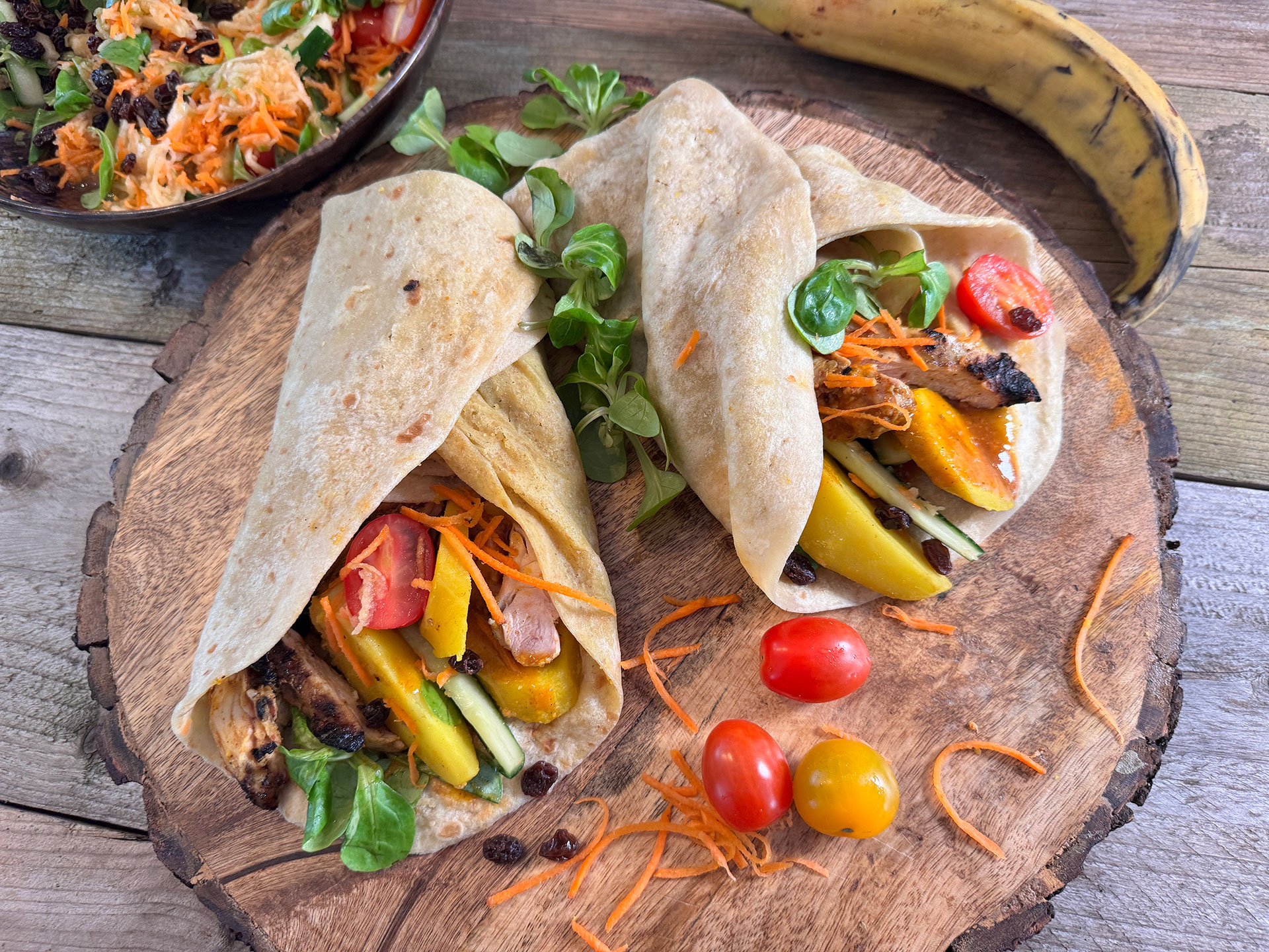 Picknick roti-rol gevuld met gegrilde masala kip, aardappel, bakbanaan, veldsla, cherrytomaat, wortel en groene appel.