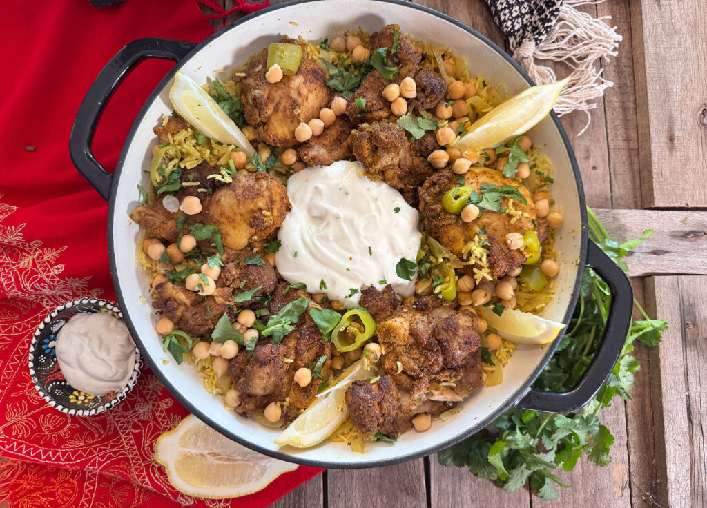 Chicken Mandi met gekruide kip, basmatirijst, kikkererwten, groene puntpaprika, koriander en knoflook-yoghurtsaus.